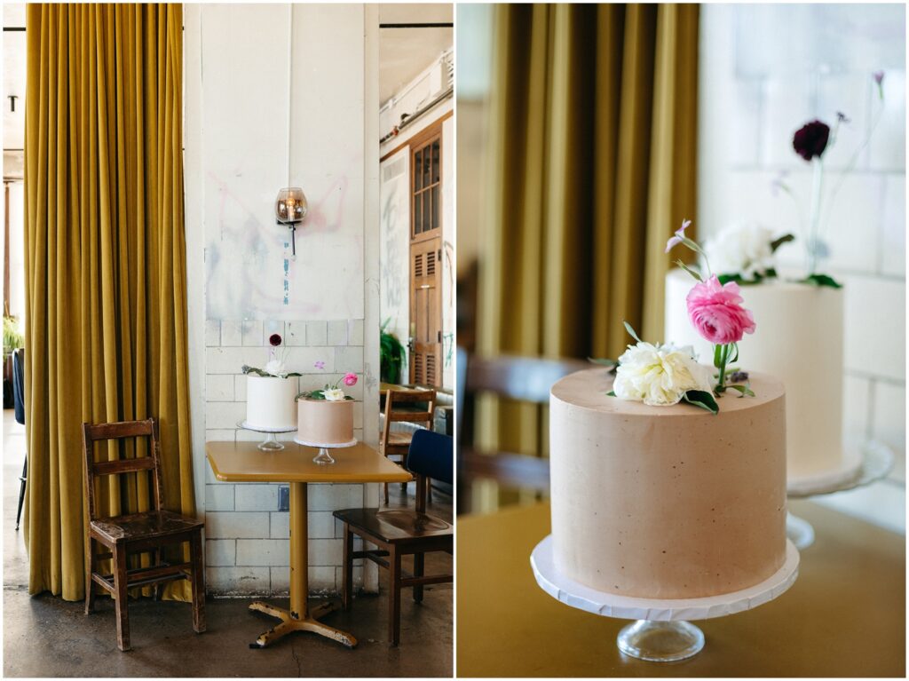 Two Philadelphia wedding cakes with pink and red flowers sit on a table beside a curtain.