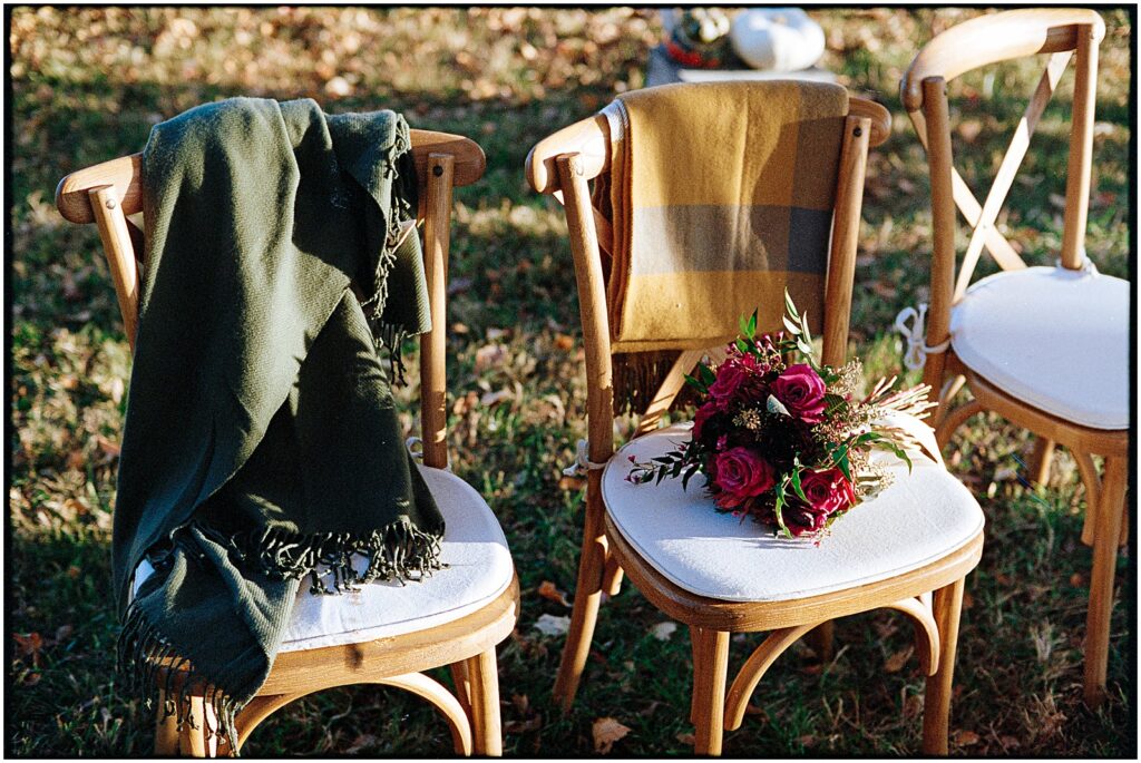 Blankets sit on ceremony chairs for a guests at an outdoor wedding in the fall.