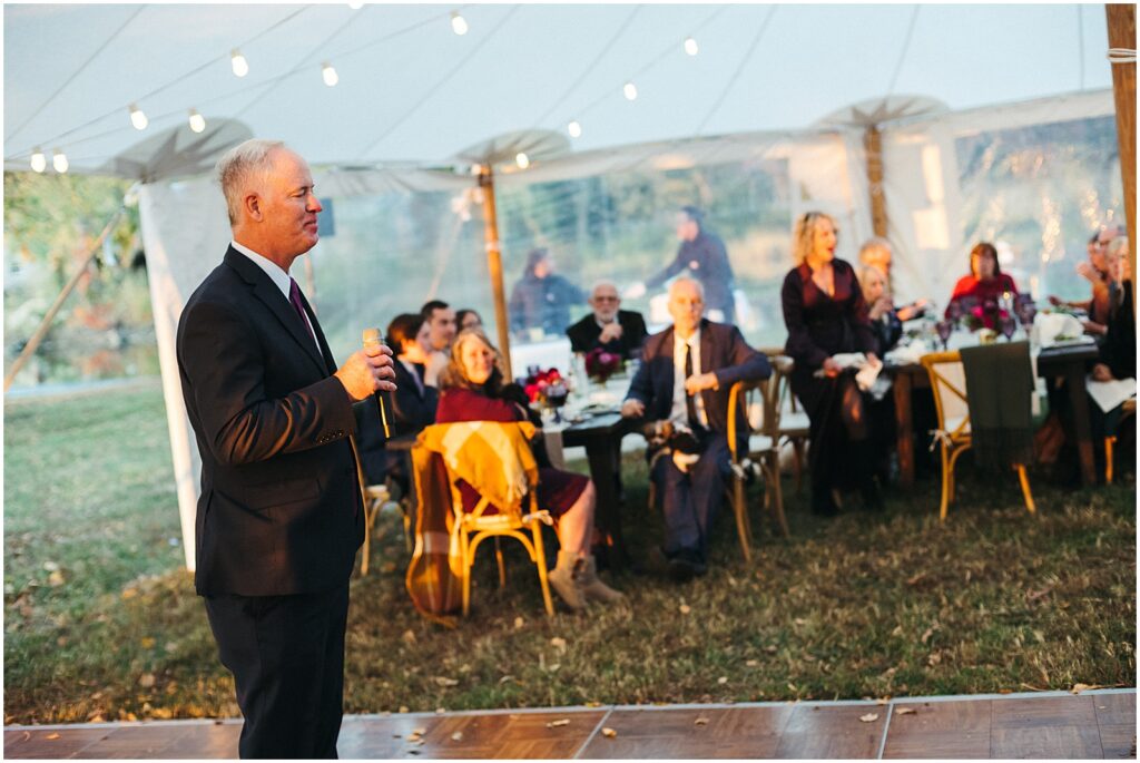 A family member gives a speech in a wedding tent.