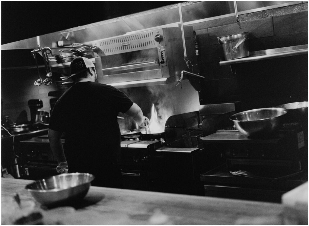 A cook stirs food on a pan in the open kitchen at Barbuzzo.