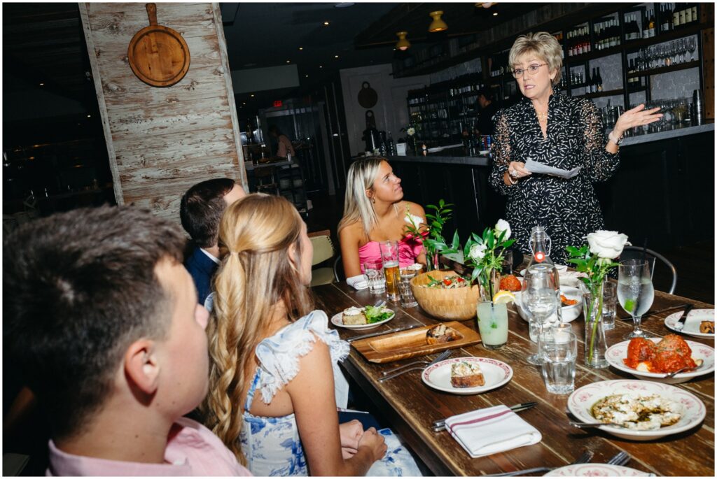 A woman gives a speech at a rehearsal dinner.