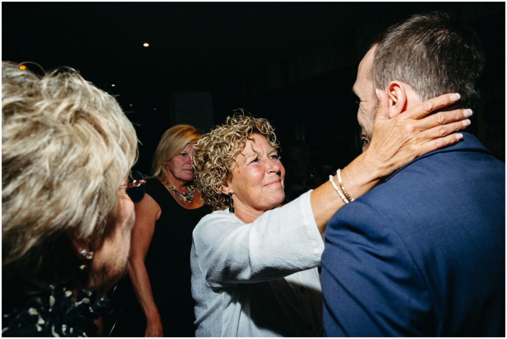A woman places her hands on a groom's cheeks.
