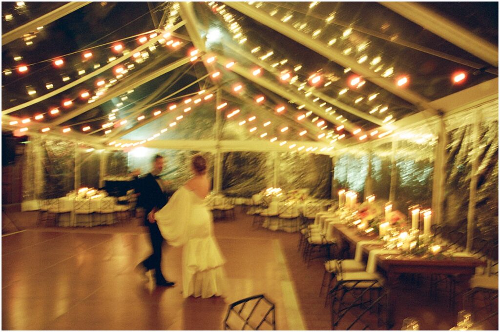 A bride and groom dance alone in a wedding tent.