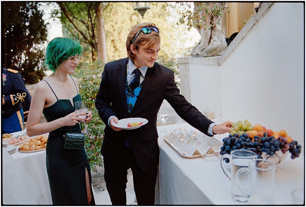 Wedding guests take fruit from a bowl on a buffet table.