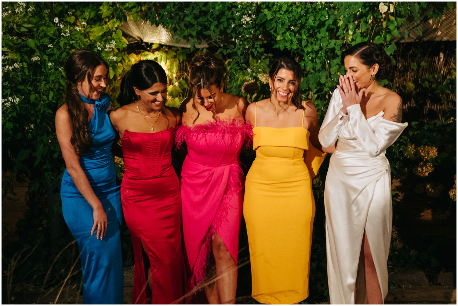 The bride admires her bridesmaids colorful dresses.